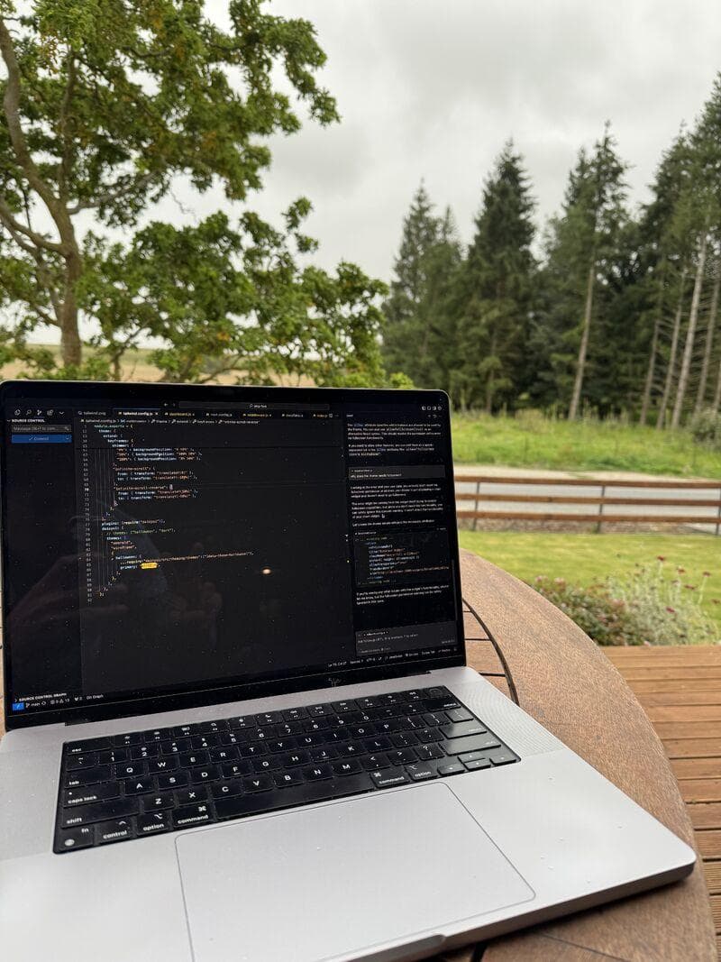 Mijn laptop met code open, buiten aan een houten tafel